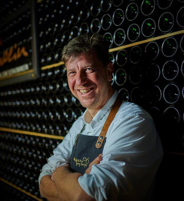 Jörg Geiger vor einem Weinregal
