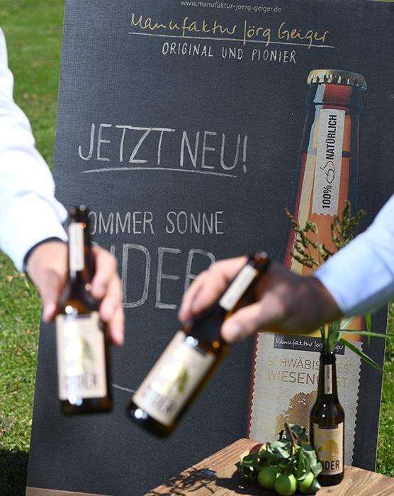 2 Personen stoßen mit einer Flasche Cider an